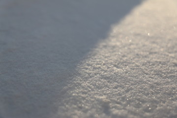 Close up of white snow, with sunlight taking one half and the shadow taking up the other half. 