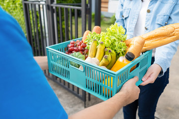 Food Deliver Asian man in blue uniform give fruit and vegetable to receiver customer front house,...