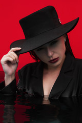 portrait of a fashion girl dressed in a classic jacket and a black hat in water