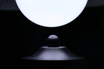 An LED light shines on a black, plastic decoration of the lamp. 