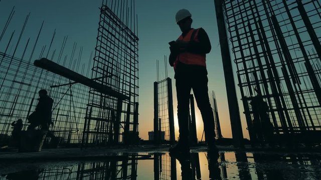 Male foreman checks work of builders on a site.