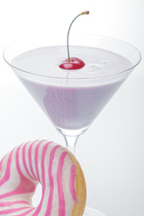  a glass of martini and a pink and white striped donut close-up. photo for the screensaver. In a glass of milkshake milkshake. One cherry on top. - 353352883