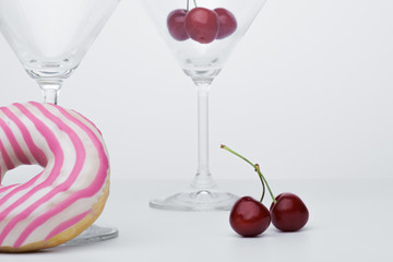  A flower in a glass close-up for a screensaver. In the background is a donut glass. And next to it is sweet cherry.