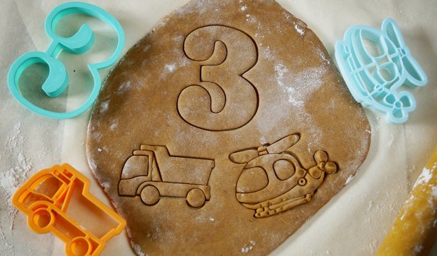 The rolled out dough is on the table. Different figurines are cut out of the dough with moulds. The cutting moulds are made of plastic on a 3 d printer. Shape in the form of number 3, machine and