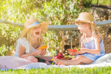 Two happy little girls on picnic in the garden