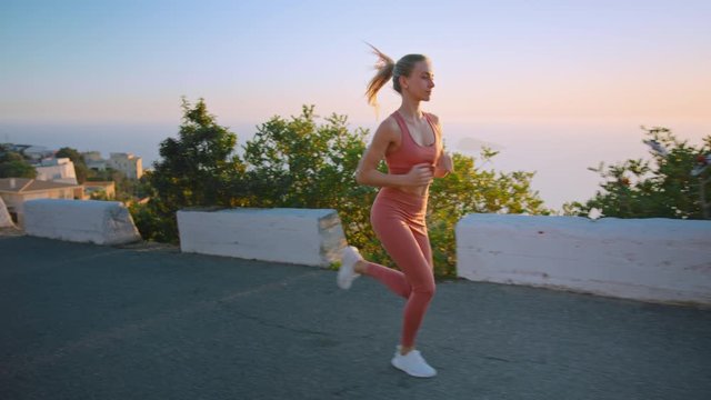 Fit strong athletic woman on early morning workout routine. Young empowered female on road to success run sprint to stay fit and healthy. Solo lonely workout concept, social distance in morning hours