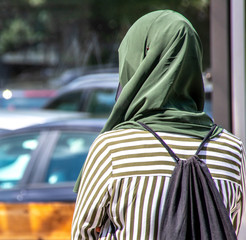 A girl on the street with head covered with a green scarf