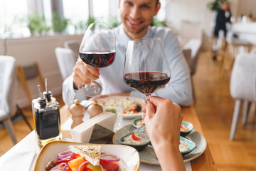 Smiling young man and woman toasting with wine in restaurant