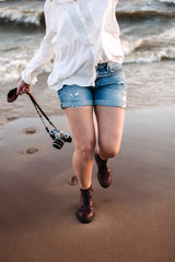 young woman walking on the beach with camera