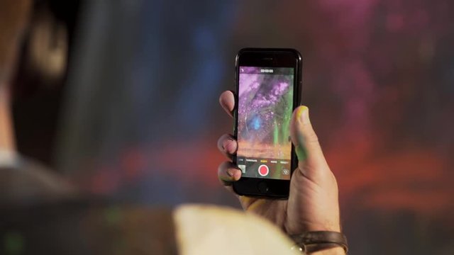 close-up of a smartphone screen as an artist throws paint on a canvas painting