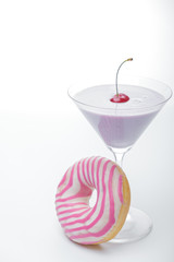  a glass of martini and a pink and white striped donut close-up. photo for the screensaver. In a glass of milkshake milkshake. One cherry on top. - 353355040