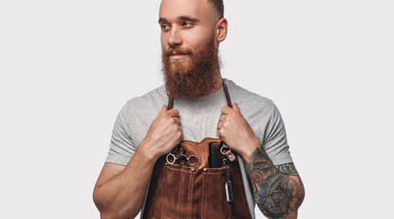 Stylish barber in apron looking away