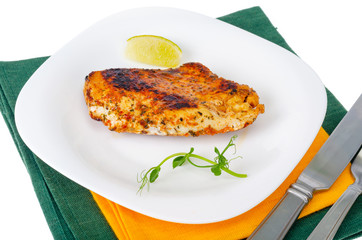Piece of fried chicken with spices on white plate.