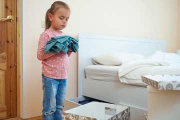 Little girl putting clothes to card box for donation