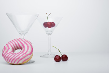  A flower in a glass close-up for a screensaver. In the background is a donut glass. And next to it is sweet cherry.