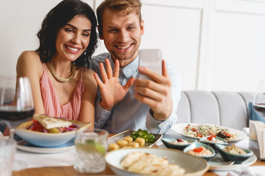 Beautiful young couple chatting with friend through video call