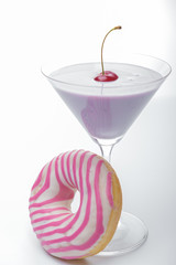  a glass of martini and a pink and white striped donut close-up. photo for the screensaver. In a glass of milkshake milkshake. One cherry on top. - 353356846