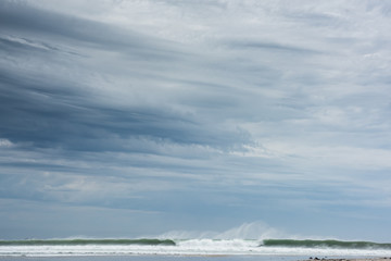 storm clouds over ocean with a big wave breaking.