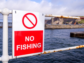no fishing sign in front of the sea at the pier