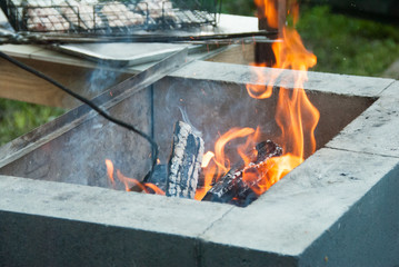 Firewood burning in the grill. Fire flames. B-B-Q meat at the background. Close up
