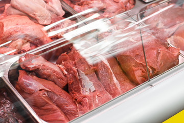 Heap of fresh meat food meat food background in supermarket store. Different types of raw meat in plastic boxes, leg of lamb on the bone, beef tail, beef neck, beef blade. Concept of farm and raw