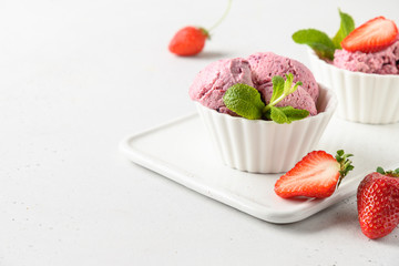 Homemade strawberry ice cream in bowls on white. Close up.
