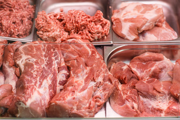 Heap of fresh meat food meat food background in supermarket store. Different types of raw meat in plastic boxes, leg of lamb on the bone, beef tail, beef neck, beef blade. Concept of farm and raw