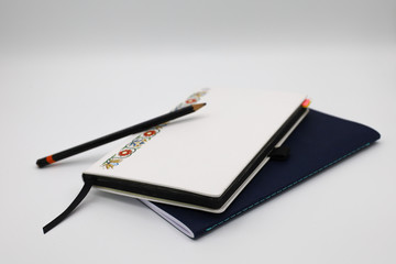 Two notebooks and a pencil with a white background