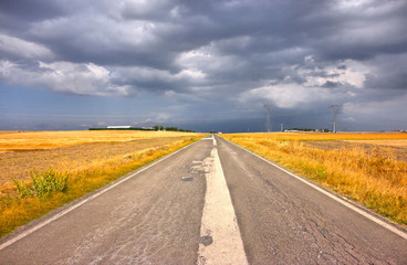 completely empty country road in the middle of the wheat field to nowhere with storm cloudy summer sky   south italy matera
