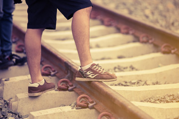 Lonely journey.Man walking on rail road with warm sunlight.