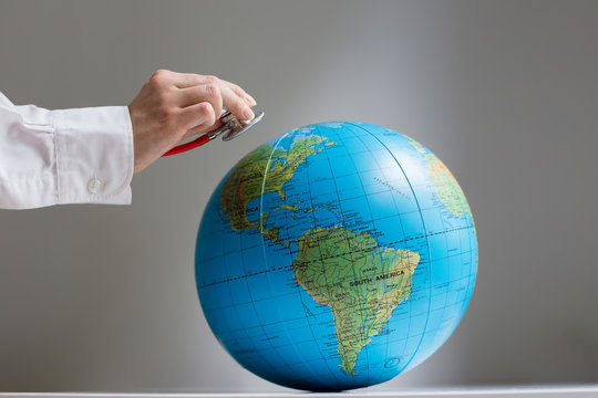 Female doctor's hand with globe and stethoscope listening breath of earth