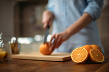 Young woman cutting orange in the kitchen