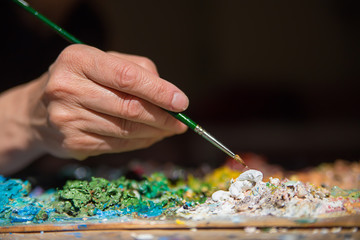 Female hand holding an artistic brush and painting 