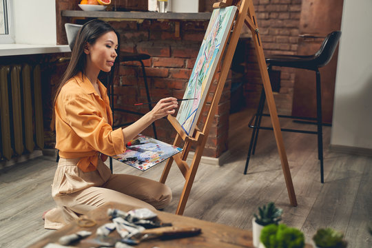 Attractive young woman painting picture at home