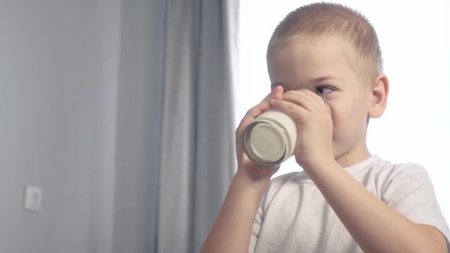 little boy drinks milk. child drinks milk from a lifestyle glass glass indoors morning breakfast