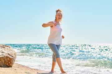 happy senior woman walks by the sea