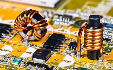 Toroidal and cylindrical inductor on circuit board of computer mainboard detail. Soldered induction...