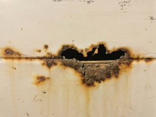 The car body is rusty and corroded. The weathered steel is penetrated damaged.