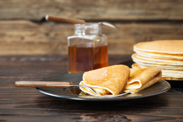 puncakes with honey and cup of tea on old wooden background