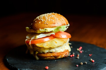 hamburger with chicken, pineapple and vegetables on a plate