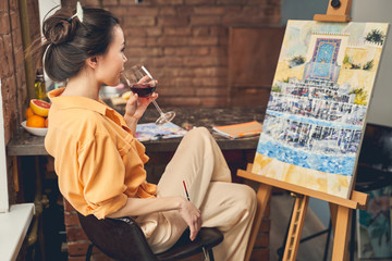 Charming lady drinking wine and looking at painting