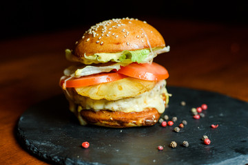 hamburger with chicken, pineapple and vegetables on a plate