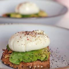 Breakfast on a plate - poached eggs on bread with avocado, close-up