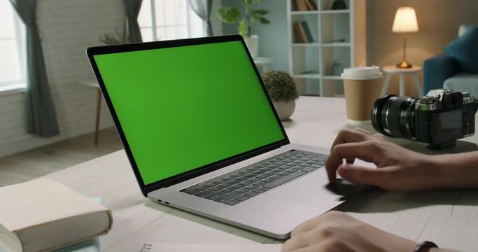 Close up shot of hands of a remote worker working on laptop computer with chroma key green screen, moving finger on trackpad - distance work, technology concept close up 4k template