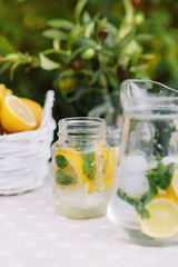 Lemonade and olive palm on table. Mason jar glass of lemonade with lemons. Copy space. Fruits and macaroons on the table. The concept of spring and summer season. Healthy Food and Drink