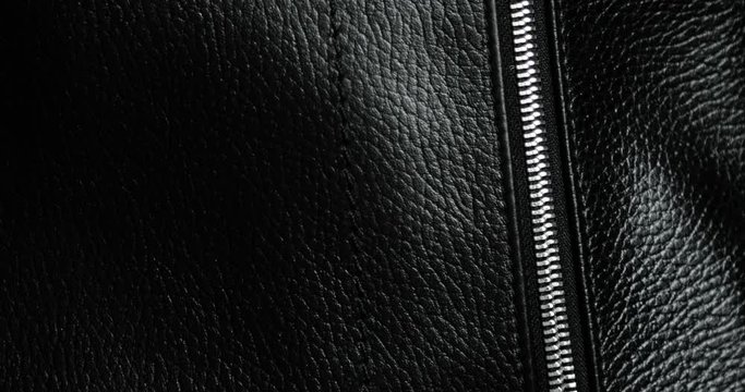 Man tests zips and unzips metal zipper on leather black bag, hand closeup view. Macro shot of unzipping and zipping metallic zipper on black leather accessory with guy's hand. Expensive brutal