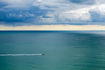 Boat sailing in the deep blue sea on the cloudy day.  Freedom concept. 