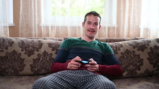 A man sits on the couch and plays the prefix at home