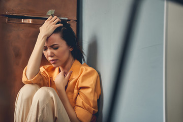 Unhappy young lady sitting on the floor at home