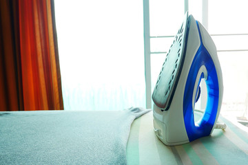 Place the iron vertically and the gray t-shirt on the table. The concept of home ironing